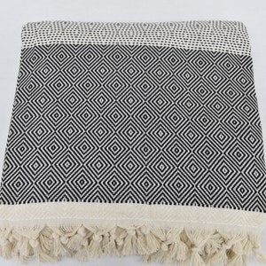 May include: A black and white diamond patterned throw blanket with fringe on the edges.