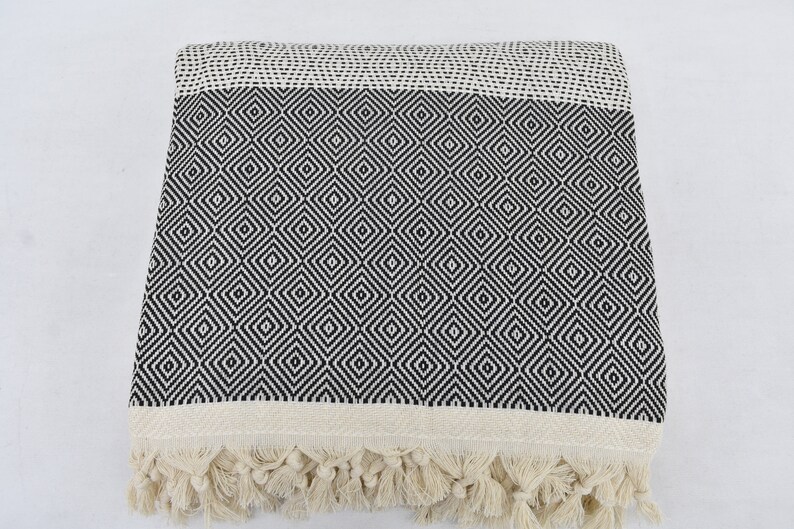 May include: A black and white diamond patterned throw blanket with fringe on the edges.