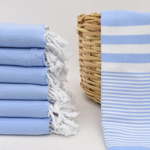 May include: A stack of light blue and white striped towels with white fringe. The towels are folded and stacked on a white surface.