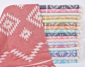 Pode incluir: Uma coleção de toalhas turcas em várias cores, incluindo vermelho, rosa, azul bebê, mostarda, verde pistache, cinza, laranja, verde, azul marinho, rosa claro, rosa claro em pó, azul claro, rosa escuro, menta, azul, roxo, cinza claro e turquesa. As toalhas apresentam um padrão geométrico com triângulos brancos sobre um fundo colorido.