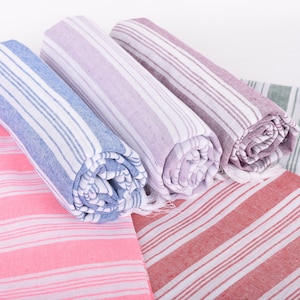 Puede incluir: Toallas a rayas enrolladas en tonos rosa, azul, morado, rojo y verde. Las toallas tienen rayas blancas y un borde con flecos. Las toallas est&aacute;n hechas de un material suave y absorbente, ideal para el ba&ntilde;o o la playa.