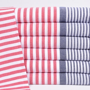 以下が含まれることがあります： 赤と白のストライプのタオルが、右側に青いストライプが入って積み重ねられています。タオルは白いフリンジが付いています。