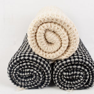 May include: Two rolled up waffle weave towels, one black and white and one cream colored.