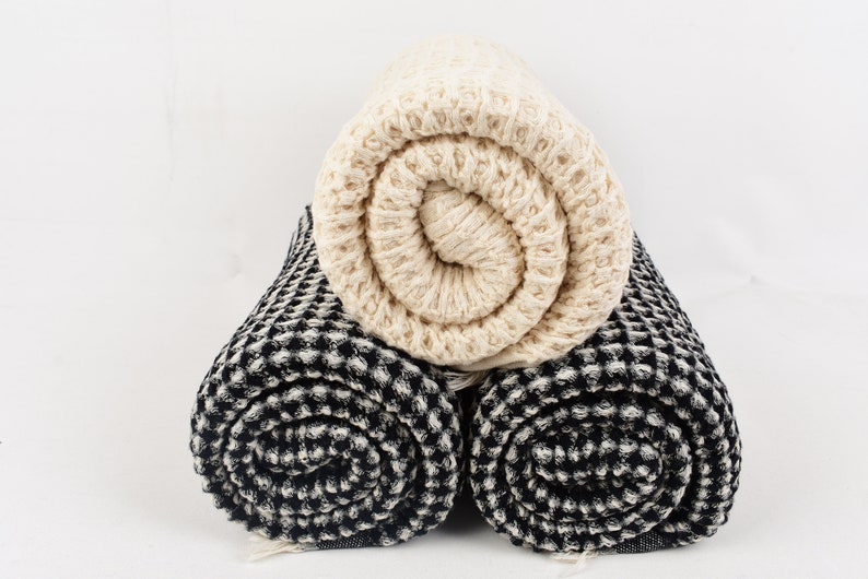 May include: Two rolled up waffle weave towels, one black and white and one cream colored.