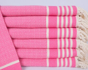 Può includere: Un mucchio di asciugamani a righe rosa e bianche con bordi a frangia. Gli asciugamani sono in cotone e hanno una texture morbida e assorbente.