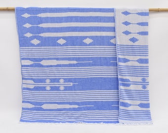 May include: A blue and white striped throw blanket with a geometric pattern. The blanket has a fringed edge.