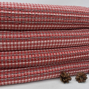 Puede incluir: Pila de cuatro toallas de color rojo y blanco con detalles negros. Las toallas tienen un borde con flecos y están dobladas cuidadosamente.