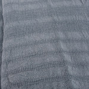 May include: A close-up of a gray textured fabric with a subtle diamond pattern. The fabric has a soft, woven look and feel.