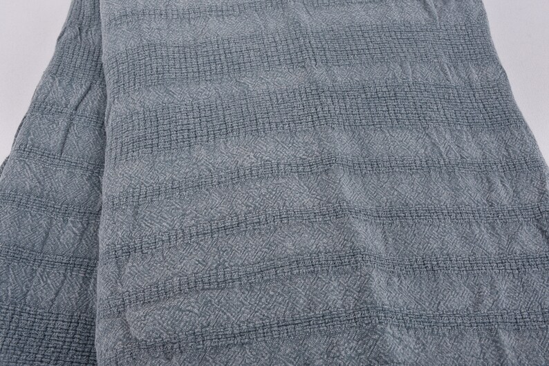 May include: A close-up of a gray textured fabric with a subtle diamond pattern. The fabric has a soft, woven look and feel.