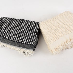 May include: Two waffle weave towels, one black and white and one cream, with fringed edges.