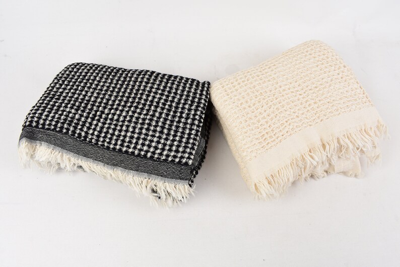 May include: Two waffle weave towels, one black and white and one cream, with fringed edges.