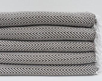 May include: A stack of folded brown and white herringbone patterned towels. The towels have a fringe on the edge. The towels are made of a soft, absorbent material.