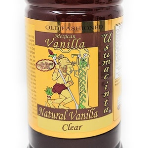 May include: A clear glass bottle of Old Fashioned Mexican Vanilla extract. The bottle has a yellow label with a cartoon illustration of a person harvesting vanilla beans. The label also says "Vanilla Beans Inside" and "Natural Vanilla Clear".