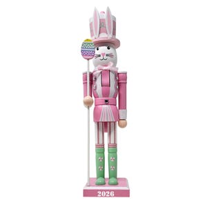 May include: A pink and white Easter bunny nutcracker figurine. The bunny wears a hat with bunny ears and holds a staff with an Easter egg design. The figurine has green boots and the number "2026" on the base.