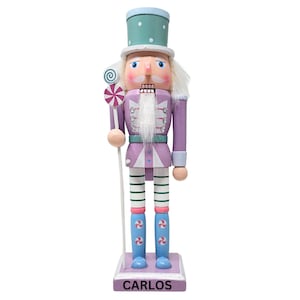 May include: A purple and white wooden nutcracker with a green hat and a candy cane in its hand. The nutcracker is standing on a base that says "CARLOS".
