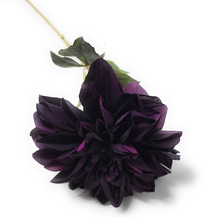 May include: A single dark purple artificial dahlia flower with a stem and leaves.