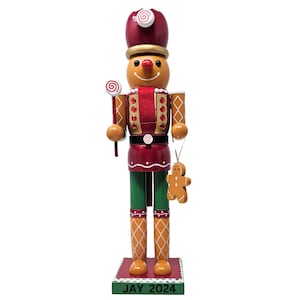 May include: A gingerbread man nutcracker with a red and gold hat, a red and white candy cane, and a gingerbread man ornament hanging from his hand. The base of the nutcracker is red and has the text "JAY 2024" on it.