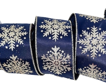 Op de afbeelding: Marineblauwe lint met gouden glitter sneeuwvlok ontwerpen. Het lint is opgerold en toont het herhalende patroon. De randen zijn afgewerkt met zilverkleurig metallic garen. Perfect voor feestelijke knutselprojecten en cadeauverpakkingen.