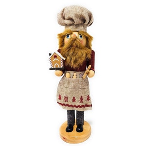 May include: A wooden Christmas nutcracker in the shape of a chef, wearing a chef's hat, glasses, and a long brown beard. The chef holds a gingerbread house and a wooden spoon. The apron has a Christmas tree pattern.