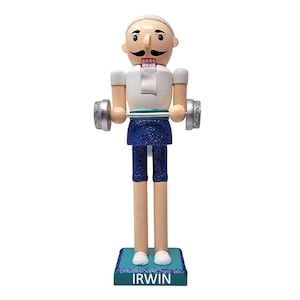May include: A wooden nutcracker figurine of a weightlifter. The figurine has a white shirt, blue shorts, and is holding a barbell with silver weights. The base is blue with the name "IRWIN" in white.