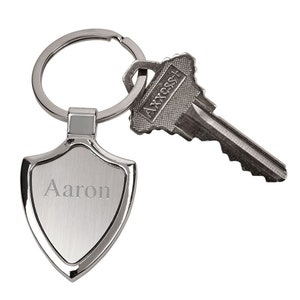 May include: Silver keychain with a shield-shaped tag engraved with the name "Aaron" and a silver key with the word "ACCESS" on it.