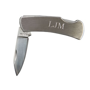 May include: A small, silver pocket knife with the blade partially open. The handle is engraved with the initials "LJM". The blade is marked "STAINLESS STEEL".