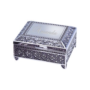 May include: A silver jewelry box with ornate floral and scrollwork designs. The box has a rectangular shape with a hinged lid and small feet. The name "Amanda" is engraved on the lid.