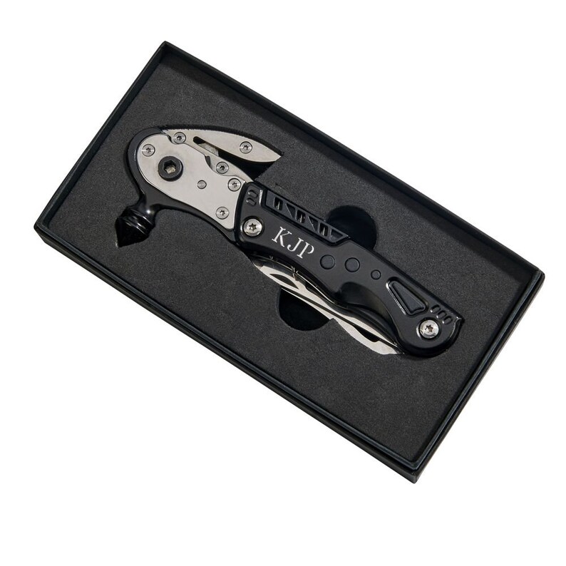 May include: A black multi-tool with a silver blade and a hammer head. The tool is engraved with the initials "KJP" and is in a black box.