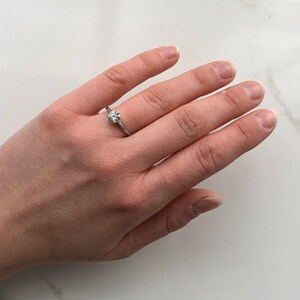 May include: A silver ring with a single round diamond set in a prong setting.