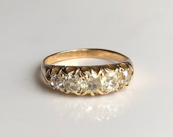 May include: A gold band ring with a row of clear round gemstones set in a delicate, openwork design.