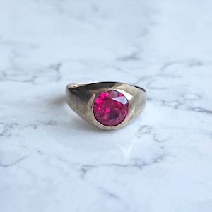 Peut inclure: Une bague en argent avec une pierre précieuse ovale rose vif.