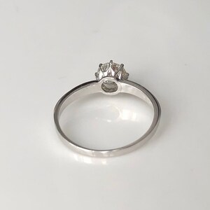May include: A silver solitaire engagement ring with a round diamond set in a prong setting.