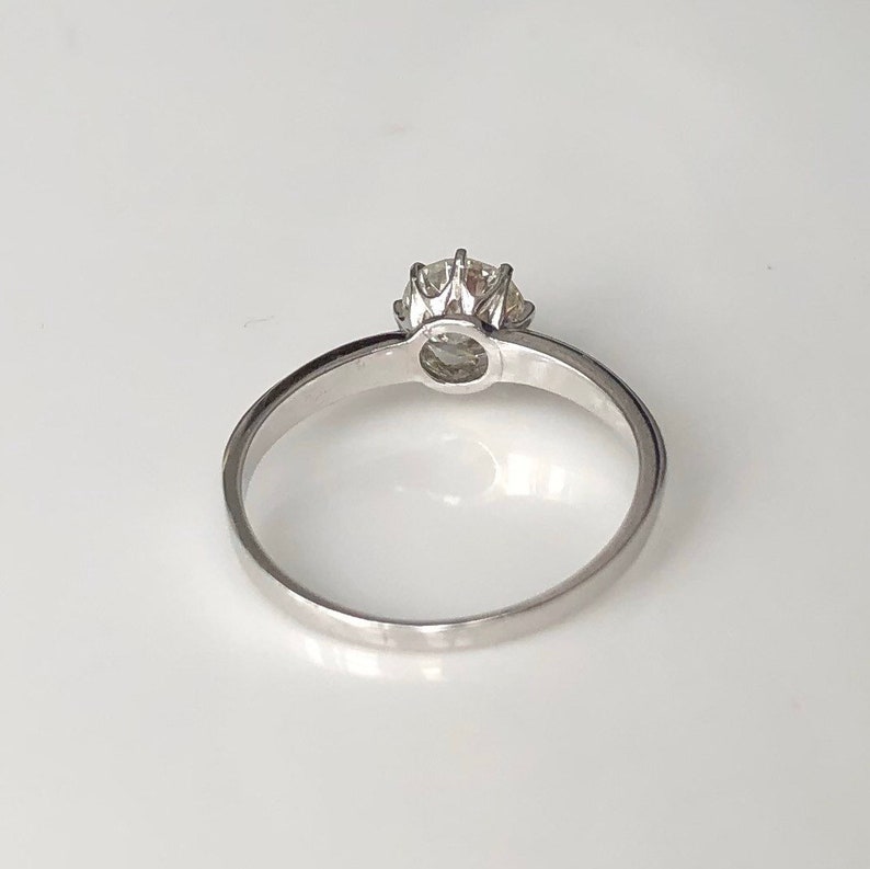 May include: A silver solitaire engagement ring with a round diamond set in a prong setting.