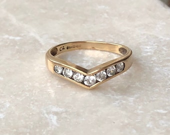 Op de afbeelding: Een gouden ring met een V-vormige rij van heldere zirkonia-stenen. De ring is gemarkeerd met "CZ 925".