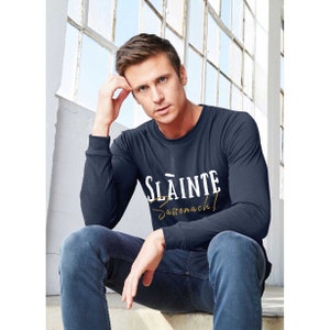 May include: A navy blue long-sleeve shirt with white text that reads "Slainte Sassenach!" in a vintage style font.