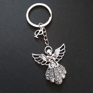 May include: Silver angel keyring with a decorative design and a letter 'P' charm attached to a silver ring.