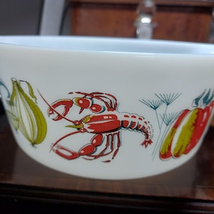 May include: White ceramic bowl with a colourful design featuring a red lobster, corn, and red peppers. The bowl has a light blue rim and is likely for serving food. The illustrations are in a vintage style.