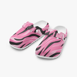 May include: A pair of pink and black zebra print clogs. The clogs have a white sole and a strap that can be adjusted. The clogs are made of a lightweight material and are designed for comfort and style.