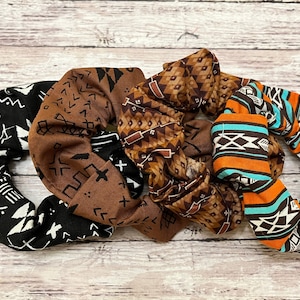 May include: Three fabric scrunchies with geometric patterns in brown, black, white, orange, and turquoise.