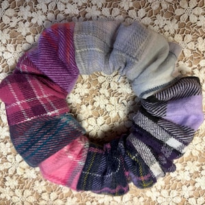 May include: A purple, pink, and blue plaid fabric hair scrunchie.