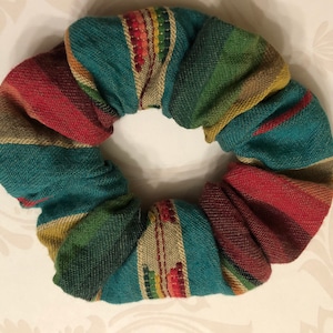 May include: A teal, red, green, and brown striped fabric scrunchie.