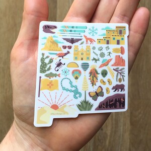 May include: A sticker of the state of New Mexico with various icons and symbols representing the state. The sticker is white with a light blue outline and features icons such as a hot air balloon, a chile pepper, a scorpion, a mountain, a church, a bat, a wolf, a butterfly, a bear, and a sunset. The text '@newmexico' is at the bottom of the sticker.