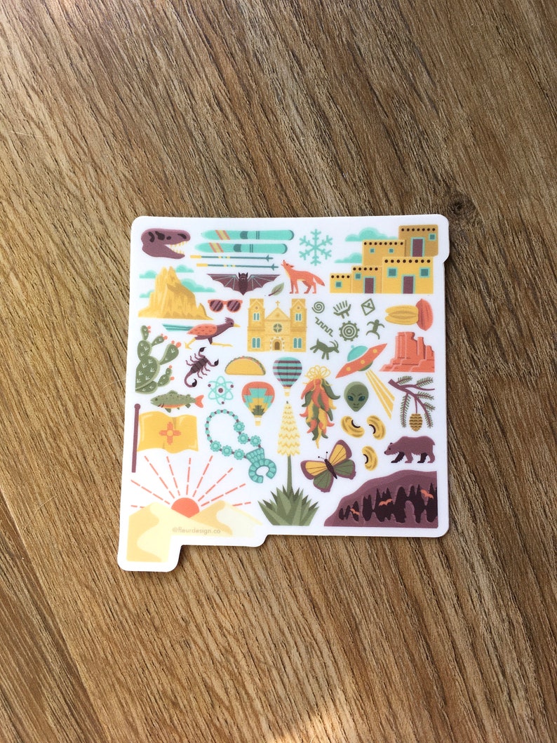 Op de afbeelding: Een witte sticker met een kleurrijke omtrek van de staat New Mexico. De sticker is gevuld met verschillende pictogrammen die de staat vertegenwoordigen, waaronder een kerk, een luchtballon, een chilipeper, een schorpioen, een beer, een vlinder en een zonsondergang. De tekst "66fourdesign.co" staat onderaan de sticker.