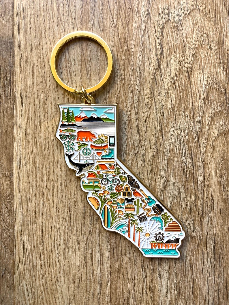 Peut inclure: Porte-cl&eacute;s en m&eacute;tal dor&eacute; en forme de l'&eacute;tat de Californie, avec un contour d&eacute;taill&eacute; de l'&eacute;tat et diverses ic&ocirc;nes repr&eacute;sentant la culture californienne, notamment un palmier, une planche de surf, une plage, un phare, un s&eacute;quoia, un ours, une montagne, un taco, un v&eacute;lo, un camping-car, une baleine, un coucher de soleil, une grande roue et le texte "TRINEN".