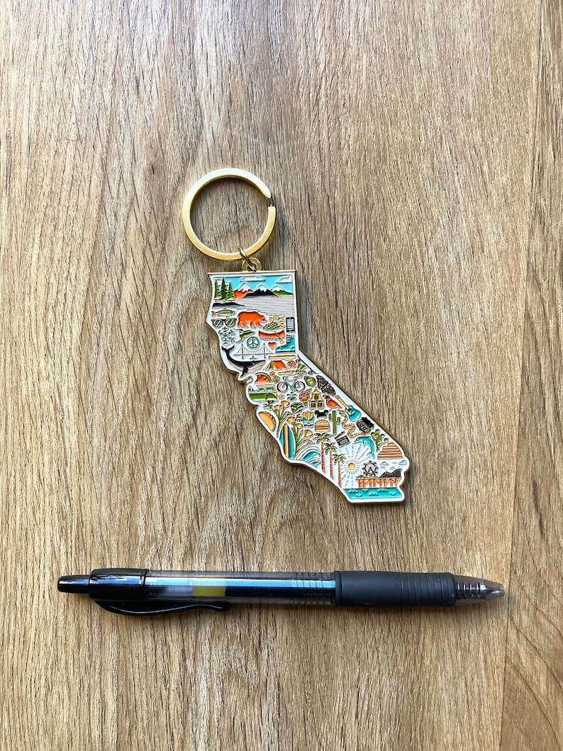 Peut inclure: Un porte-cl&eacute;s en m&eacute;tal dor&eacute; en forme de l'&eacute;tat de Californie. Le porte-cl&eacute;s est d&eacute;cor&eacute; d'illustrations color&eacute;es de divers monuments, activit&eacute;s et symboles californiens, notamment un ours, une plage, un palmier, une planche de surf et un coucher de soleil. Le porte-cl&eacute;s est dot&eacute; d'un anneau dor&eacute; fix&eacute; en haut.