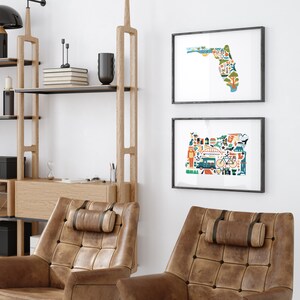 Two framed state map art prints hang on a wall. The art consists of a collection illustrated icons that form the shape of the state of Florida and Oregon. Each illustration represents that culture, natural beauty and history of the states.