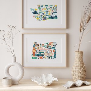 Two framed state map art prints hang on a wall. The art consists of a collection illustrated icons that form the shape of the state of Washington and Oregon. Each illustration represents that culture, natural beauty and history of the states.