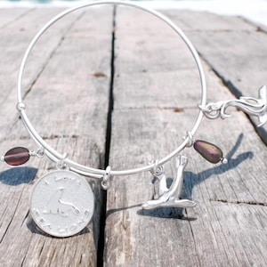 May include: Silver charm bracelet with a variety of charms, including a seal, a mermaid, and a round charm with the words "I love you more than words can say".