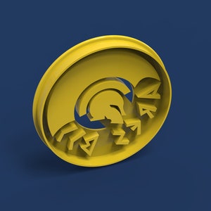 Op de afbeelding: Gele plastic koekjesvormer in de vorm van een Spartaanse helm met het woord "SPARTAN" eromheen.