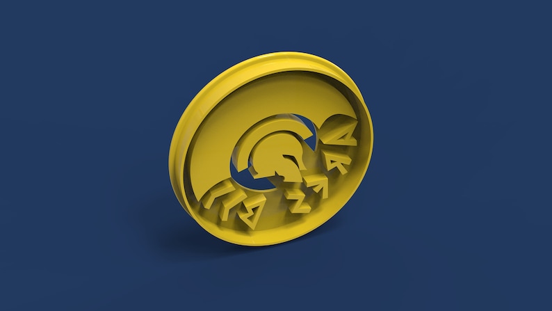 Op de afbeelding: Gele plastic koekjesvormer in de vorm van een Spartaanse helm met het woord "SPARTAN" eromheen.